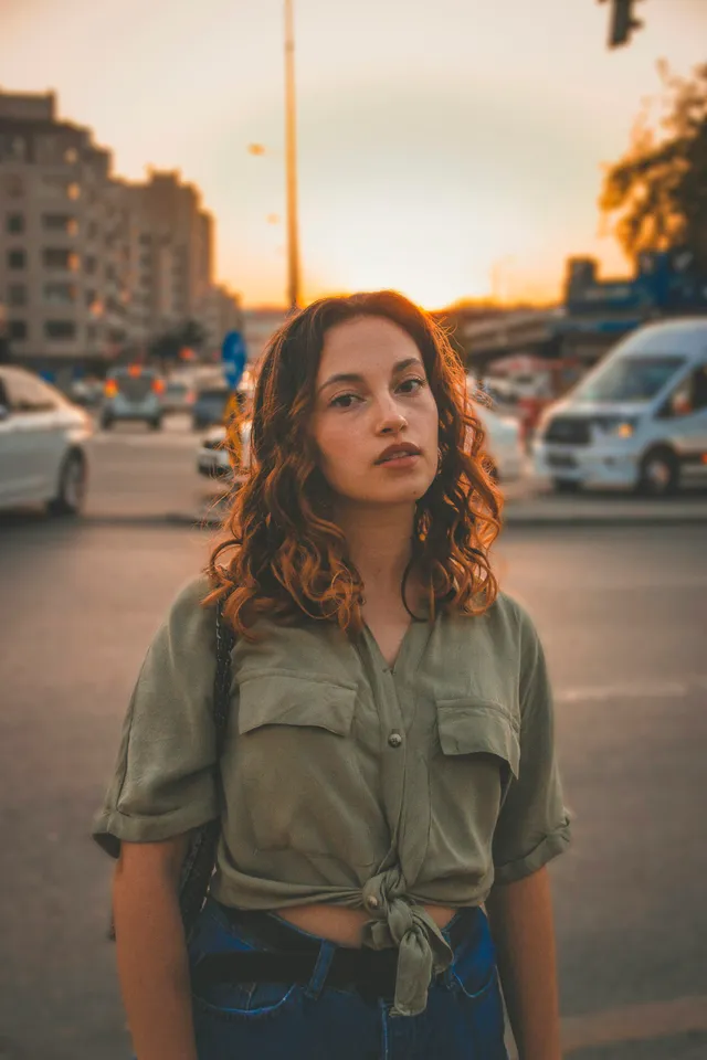 Une femme sereine dans la rue, lumière chaude de fin de journée en ville